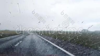 雨天从高速公路上行驶的汽车挡风玻璃上滴下的雨滴。
